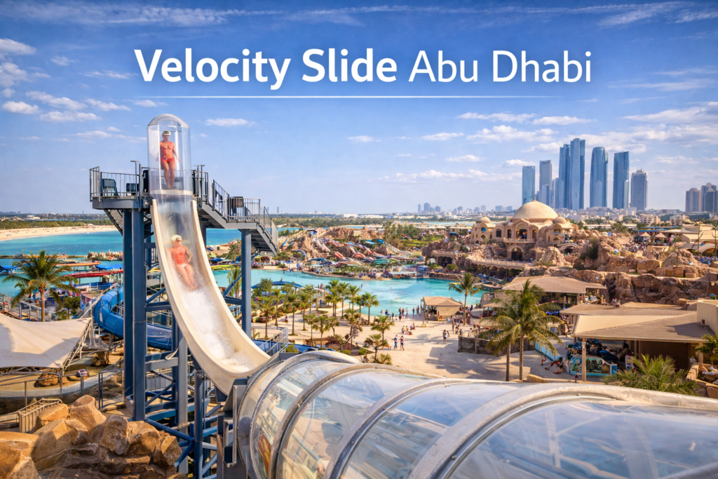 Velocity Slide Abu Dhabi at Yas Waterworld showing a near vertical waterslide tower, transparent drop capsule, water splashdown, and Yas Island skyline in bright daylight